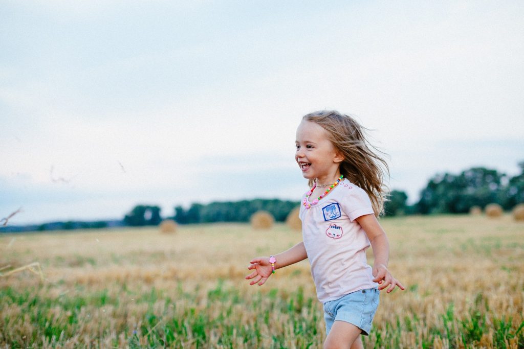 Young girl running through field smiling.