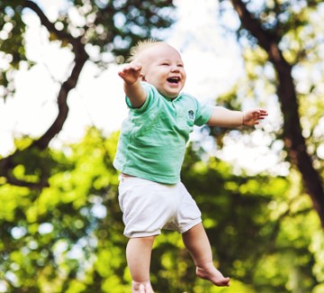 Smiling baby jumping in air.