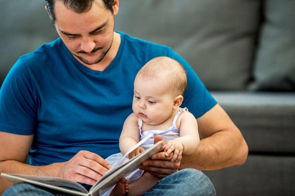 A man reading a book to his baby.