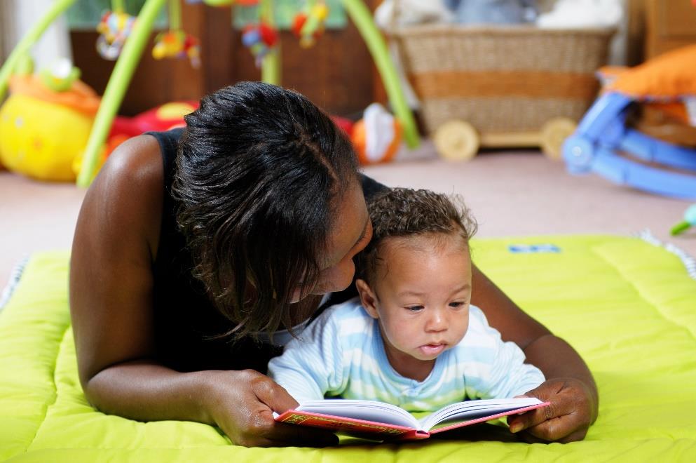 Mom reading to child as they are both laying on their stomachs.