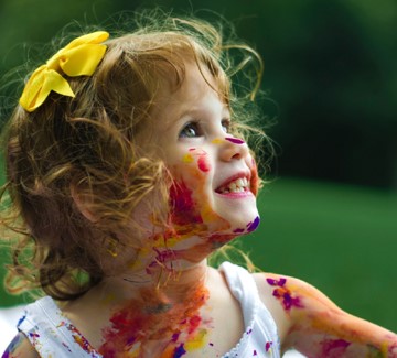 Young child smiling with paint on her face.