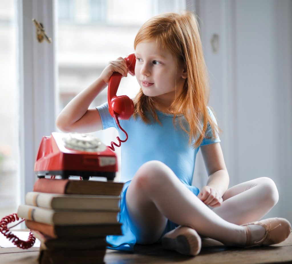 Child listening to the telephone in ballet costume.