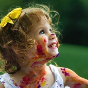 a toddler covered in paint and smiling