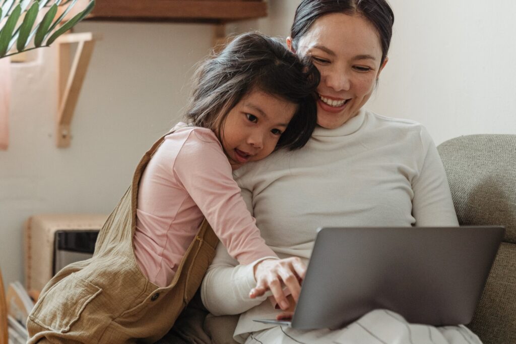 Mom and child smiling while looking at laptop.