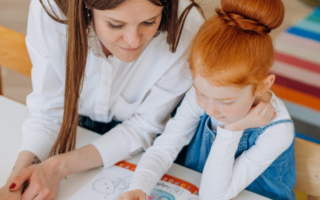 Teacher looking at drawing of young child with red hair.