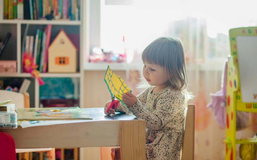 Young girl cutting picture with scissors.