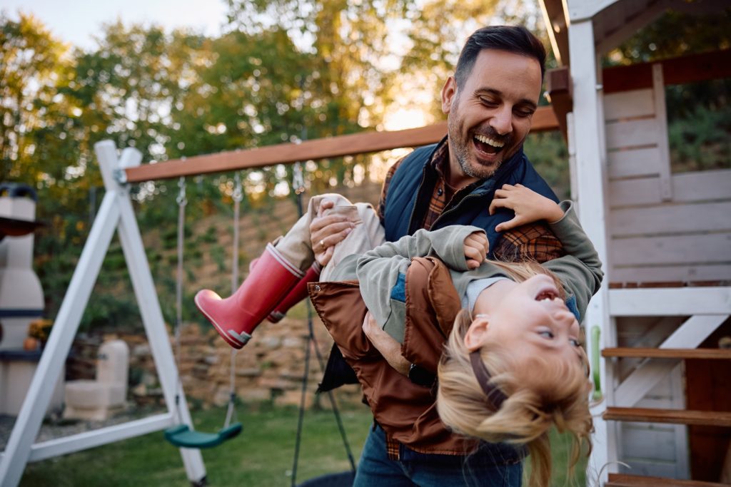 Dad laughing while holding his little girl upside down.