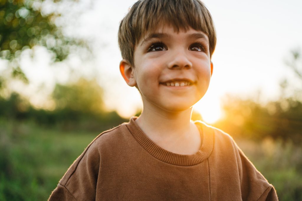 Young boy standing outside who is smiling.