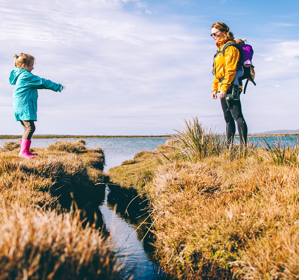 A woman and child face each other across a stream.