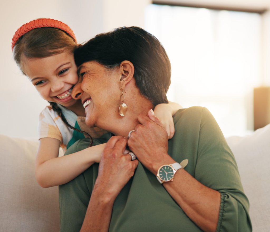 Smiling grandmother getting hug from child.