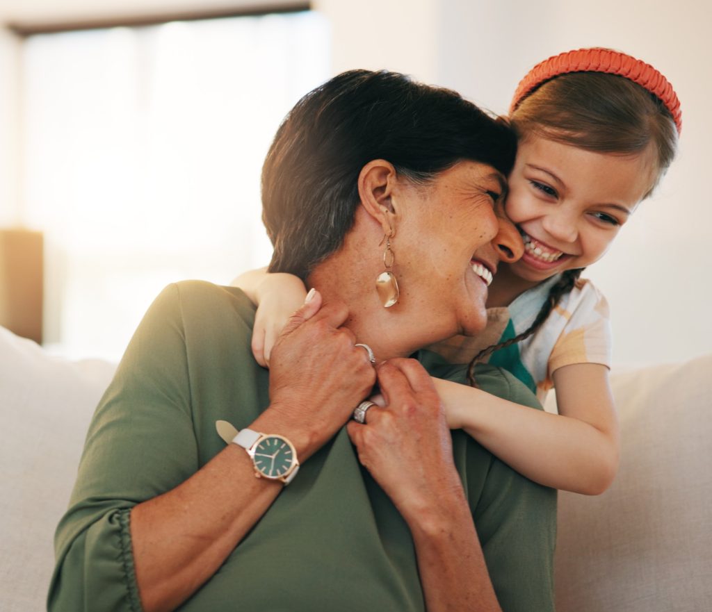 Smiling grandmother getting hug from child.