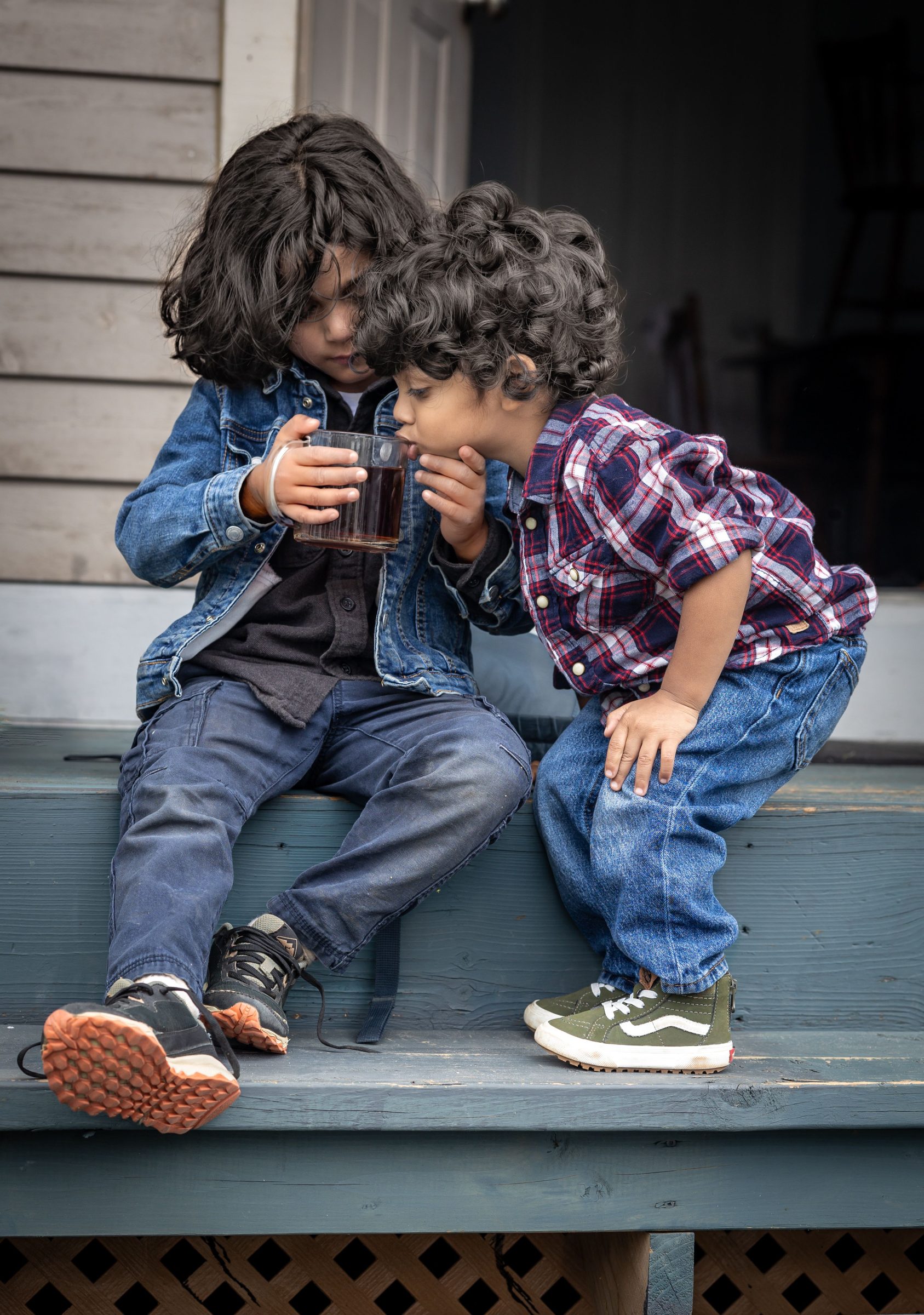 Two young siblings share a drink.