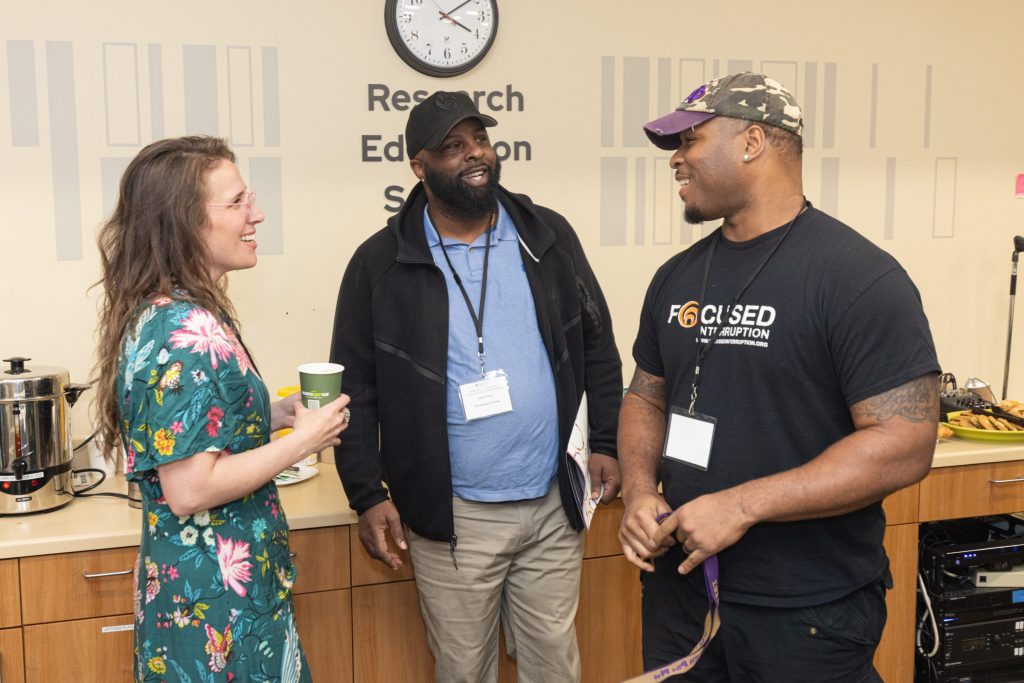 Three smiling people stand together in conversation in front of a snack selection