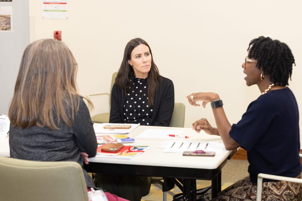 A woman speaks and gestures while two other people listen