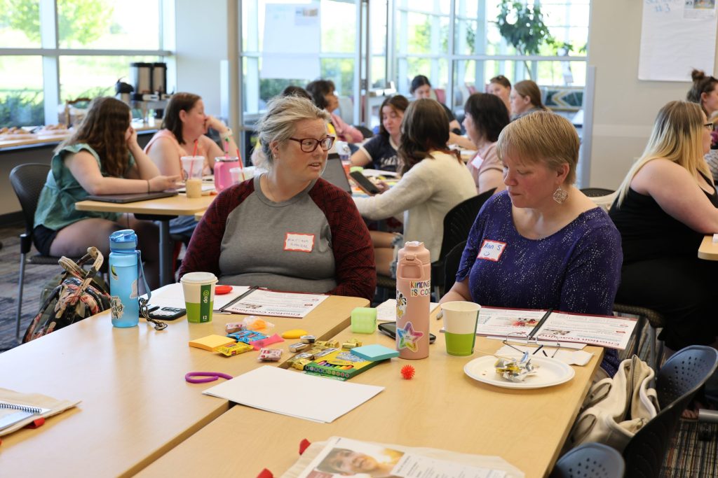 Two women talk at a table during an in-person Emotion Regulation workshop