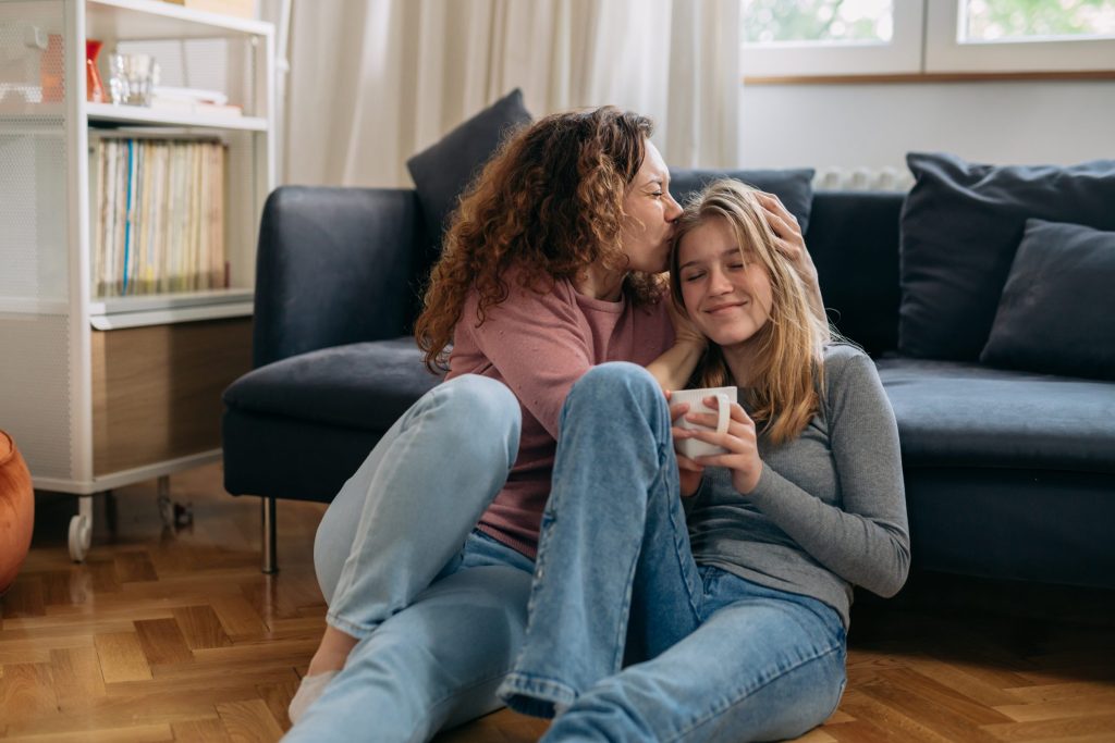 Mom kissing teen daughter's head.